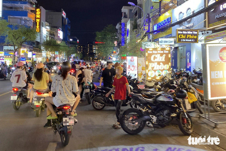 Nhiều hàng rong còn xuất hiện người đứng tràn ra giữa lòng đường Nguyễn Gia Trí để kêu gọi khách mua - Ảnh: TIẾN QUỐC