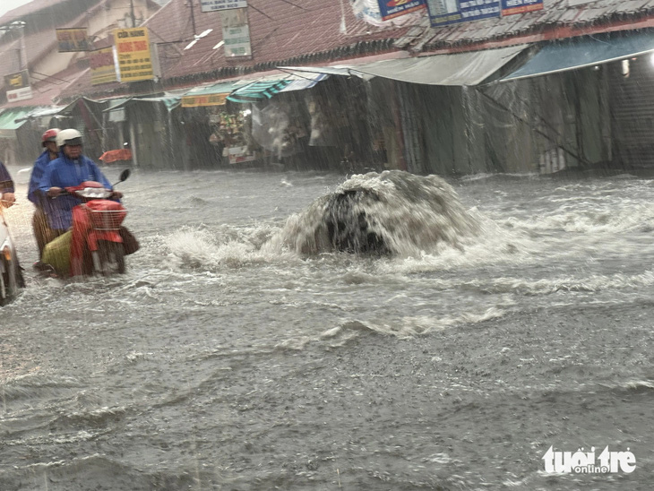 Cống thoát nước tại khu vực chợ Thủ Đức lại bung lên, nước phun ồ ạt trong cơn mưa lớn chiều 20-5 - Ảnh: NGỌC QUÝ