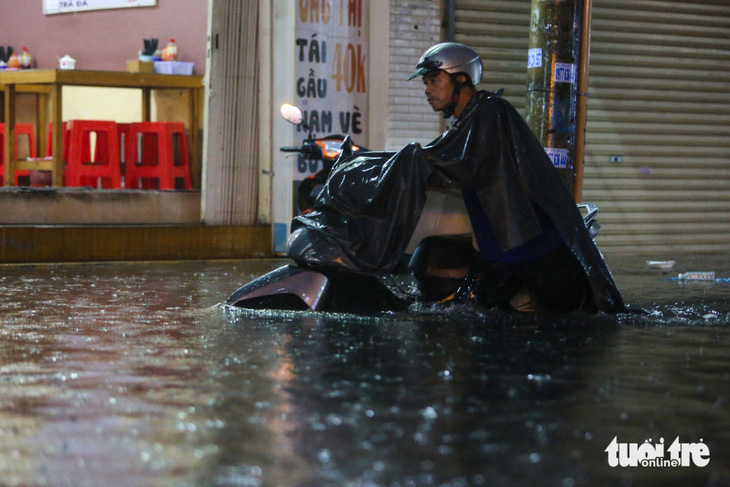 18h, mưa vẫn trút xuống đường Đặng Thị Rành khiến nước ngập lút bánh xe - Ảnh: PHƯƠNG QUYÊN