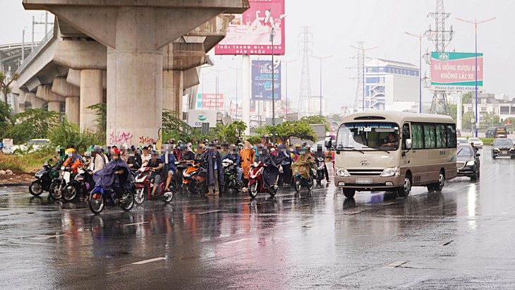 Người dân trú mưa lấn sát làn đường ô tô, cực kỳ nguy hiểm khi dòng xe đang xuống dốc cầu Sài Gòn - Ảnh: A.V