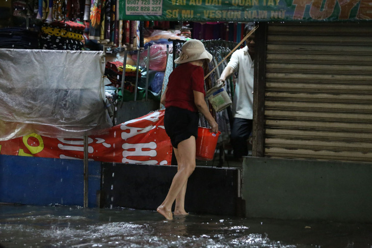 Nước vẫn tràn cả vào nhà dân khiến họ phải hì hục tát nước mỗi khi mưa ngập - Ảnh: MINH HÒA