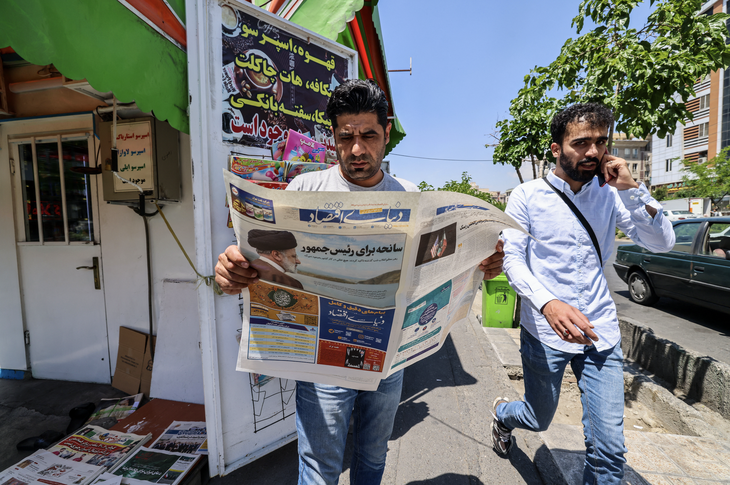 Người dân Iran đọc báo với trang bìa nói về cái chết của ông Raisi - Ảnh: REUTERS
