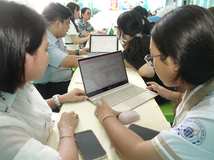 Giáo viên Trường THCS Ba Đình (Q.5, TP.HCM) hỗ trợ phụ huynh và học sinh đăng ký nguyện vọng tuyển sinh 10 trực tuyến - Ảnh: NHƯ HÙNG