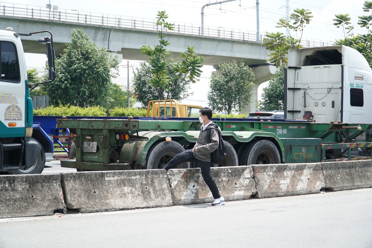 Nam sinh băng qua xa lộ Hà Nội, giữa dòng xe container đang đổ dốc - Ảnh: XUÂN ĐOÀN