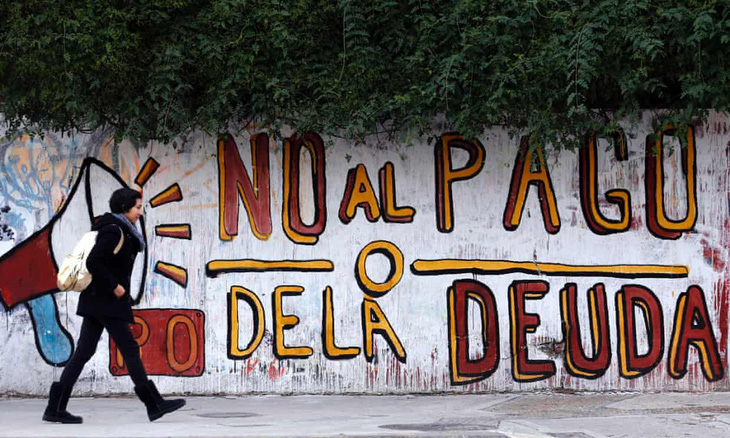 Một người phụ nữ đi ngang qua dòng chữ “Không trả nợ” ở Buenos Aires, Argentina - Ảnh: Marcos Brindicci/Reuters