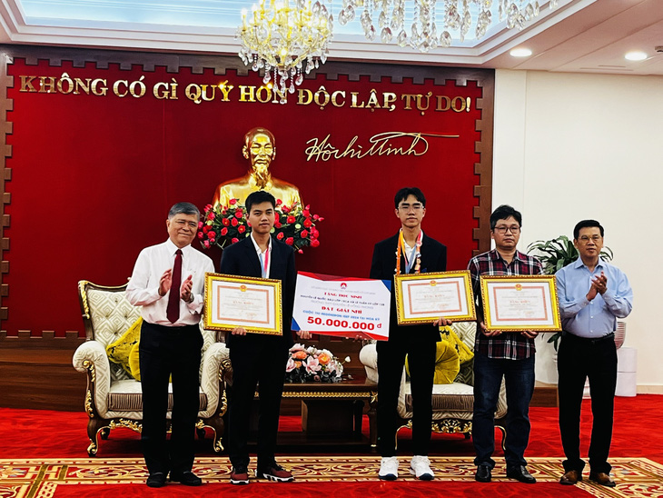 Ông Nguyễn Văn Dũng (bìa phải) - phó chủ tịch UBND TP.HCM - trao bằng khen cho hai học sinh và giáo viên hướng dẫn - Ảnh: MỸ DUNG