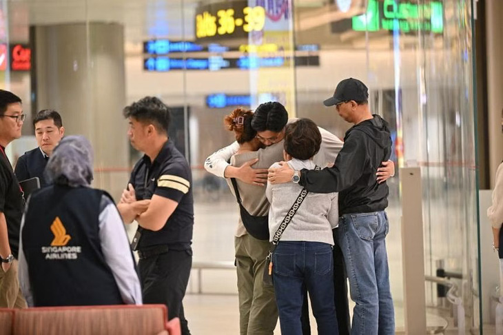 Hành khách gặp nạn trên chuyến bay của Singapore Airlines ôm người thân sau khi tới Singapore an toàn - Ảnh: STRAITS TIMES