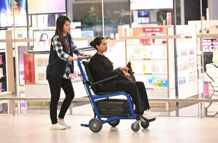 Một hành khách trên chuyến bay SQ321 được đẩy ra trên xe lăn khi đến sân bay Singapore - Ảnh: STRAITS TIMES