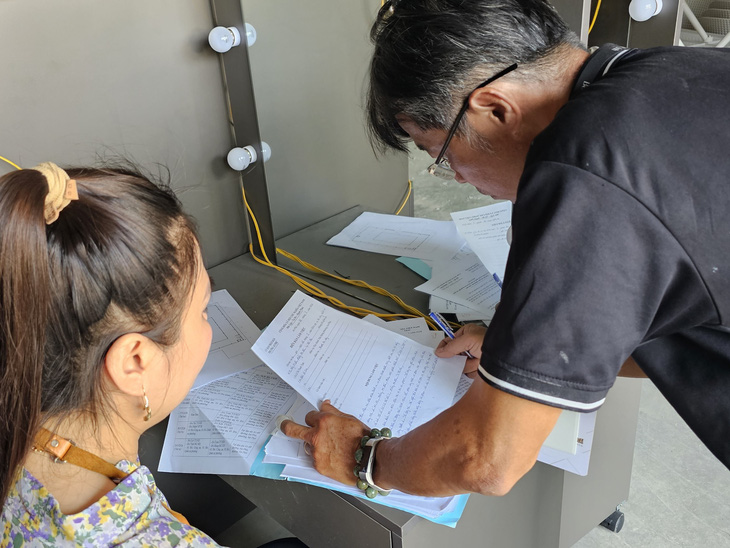 Đại diện bên tổ chức thi công (áo đen) ký biên bản với đại diện UBND phường An Phú về việc dừng thi công, tiến hành tháo dỡ diện tích vi phạm - Ảnh: ÁI NHÂN