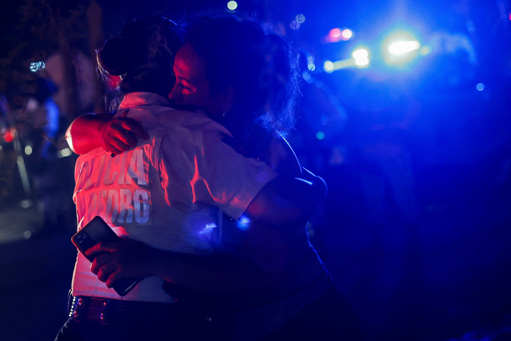Một người phụ nữ ôm sĩ quan cảnh sát khi đang tìm kiếm người thân bị mất tích - Ảnh: REUTERS