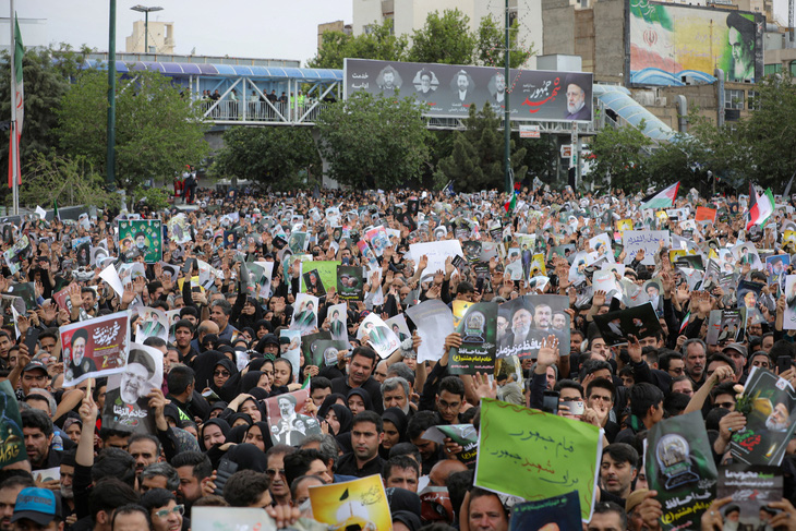 Người dân cầm theo vô số ảnh của cố Tổng thống Raisi trong ngày an táng - Ảnh: REUTERS