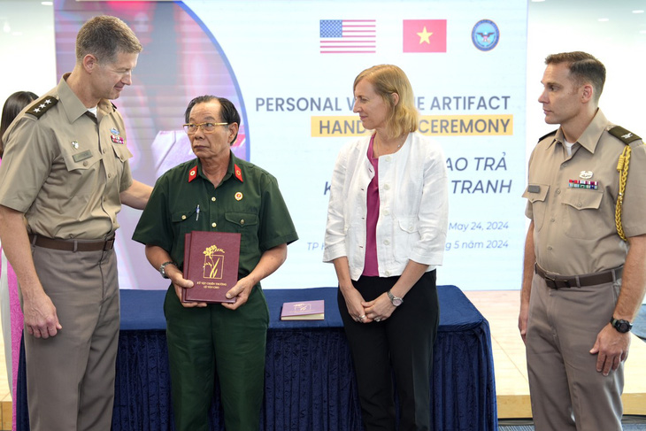 Ông Trần Văn Bản nhận kỷ vật của các đồng đội từ trung tướng Mỹ James Jarrard ngày 24-5 - Ảnh: Nguyễn Hữu Hạnh