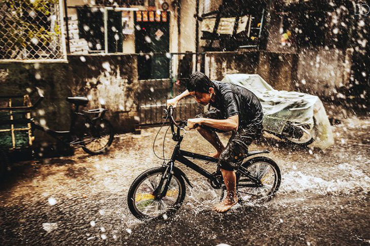 Cậu bé đạp xe trong màn mưa Sài Gòn - Ảnh: DOÃN QUANG 