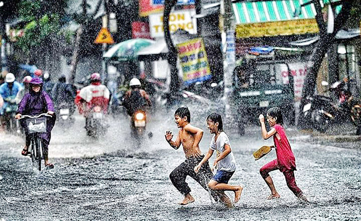 Trẻ em vui đùa tắm mưa trên đường - Ảnh: FLICKR