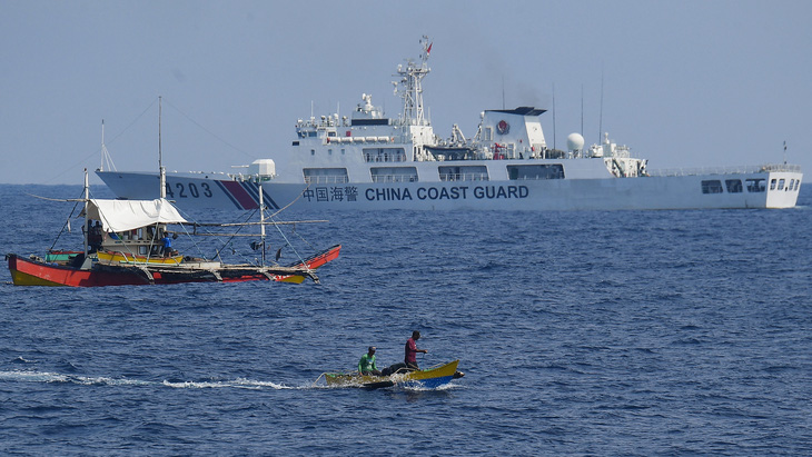 Tàu hải cảnh Trung Quốc theo dõi các ngư dân Philippines trên một chiếc tàu gỗ trong lúc nhóm Atin Ito tiếp tế nhiên liệu và thực phẩm cho ngư dân trên Biển Đông hôm 16-5-2024 - Ảnh: AFP