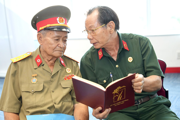 Ông Trần Văn Bản (phải) cùng ôn lại kỷ niệm lưu giữ trong kỷ vật của các đồng đội - Ảnh: NGUYỄN HỮU HẠNH