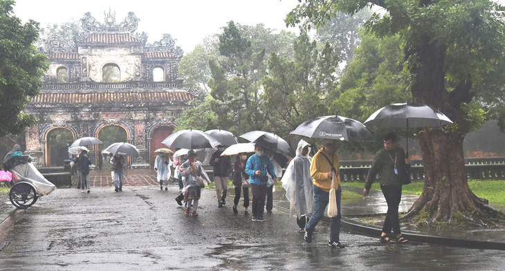 Du khách thăm Hoàng thành trong màn mưa Huế - Ảnh: ĐĂNG HẠNH