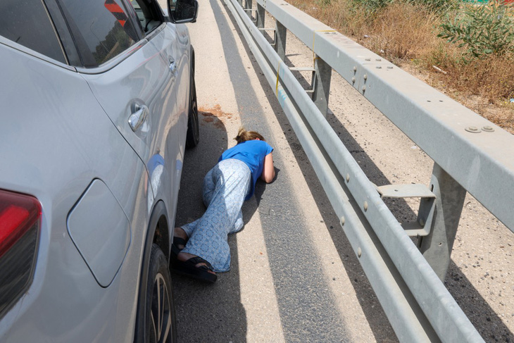 Một phụ nữ Israel nằm sát xuống mặt đường khi rocket được phóng từ Dải Gaza, gần thành phố Herzliya của Israel vào ngày 26-5 - Ảnh: AFP