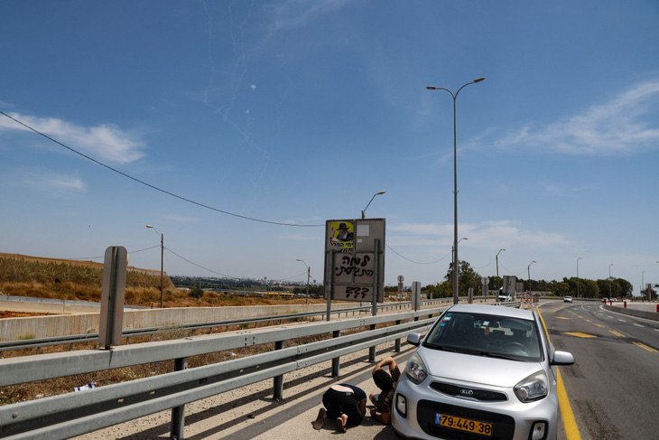 Người dân Israel nằm xuống đất nấp khi tên lửa từ hệ thống phòng không Vòm sắt (Iron Dome) của Israel đánh chặn các rocket phóng từ Dải Gaza, gần thành phố Herzliya của Israel ngày 26-5 - Ảnh: AFP