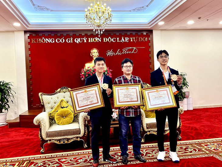 Thầy Đỗ Quốc Anh Triết cùng 2 học trò nhận bằng khen của UBND TP.HCM trong lễ đón tại sân bay Tân Sơn Nhất - Ảnh: MỸ DUNG