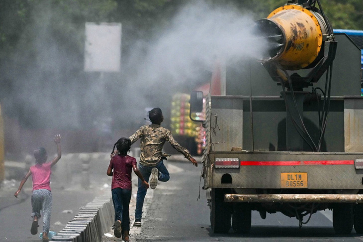 Trẻ em chạy sau xe tải phun nước ở thủ đô New Delhi, ngày 28-5 - Ảnh: AFP
