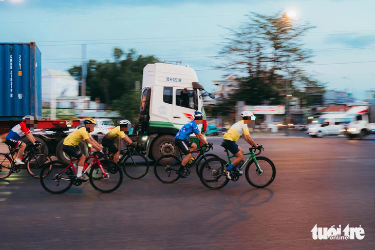 Một nhóm đạp xe dàn hàng ngang "đua" với xe đầu kéo vào lúc 5h sáng 3-5 trên đường Phạm Văn Đồng - Ảnh: THANH HIỆP
