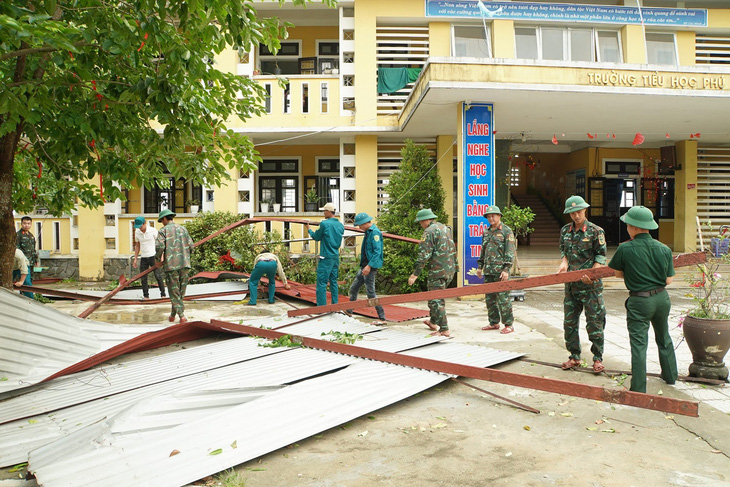 Lực lượng quân đội hỗ trợ Trường tiểu học Phú Lương 1 dọn dẹp, khắc phục hậu quả do trận lốc xoáy chiều tối 2-5 gây ra - Ảnh: LÊ SÁU