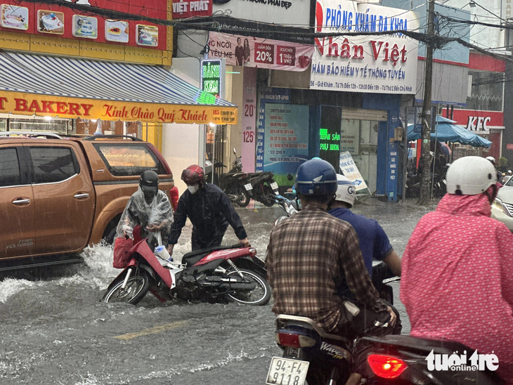 Nước chảy xiết khiến nhiều xe máy bị ngã trên đường Lê Văn Việt, TP Thủ Đức - Ảnh: NGỌC QUÝ