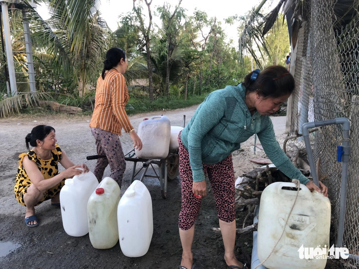 Người dân các huyện phía đông tỉnh Tiền Giang dùng can nhựa hứng nước miễn phí tại các vòi công cộng dọc đường - Ảnh: HOÀI THƯƠNG