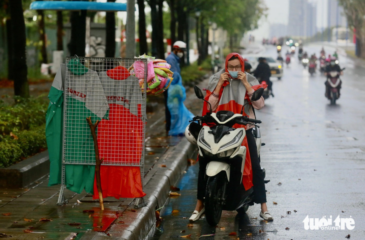 Một số người đi xe máy tấp bên đường Mai Chí Thọ (TP Thủ Đức) để mặc áo mưa. Ghi nhận khoảng 6h ngày 4-5 - Ảnh: CHÂU TUẤN