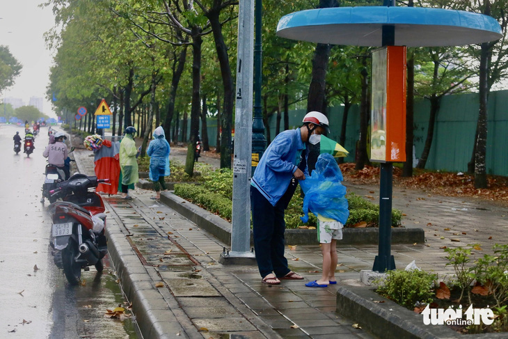 Các em nhỏ được người lớn mặc vội áo mưa. Hình ảnh ghi nhận trên đường Mai Chí Thọ (TP Thủ Đức) - Ảnh: CHÂU TUẤN