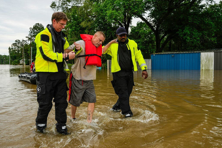 Một người đàn ông được các thành viên của Sở Cứu hỏa cộng đồng ở New Caney, bang Texas đưa ra khỏi dòng nước lũ hôm 3-5 - Ảnh: HOUSTON CHRONICLE