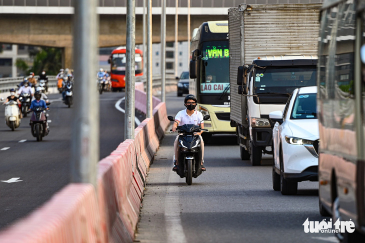 Nhiều xe máy vẫn băng băng đi vào cầu Mai Dịch cũ dù cây cầu này đã được tách ra để chuyên phục vụ các ô tô đi vào đường cao tốc - Ảnh: HỒNG QUANG