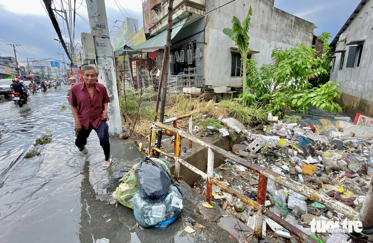 Sau cơn mưa, nước đã rút dần nhưng rác vẫn còn đọng lại nhiều ở con rạch sát đường Tô Ngọc Vân - Ảnh: CHÂU TUẤN