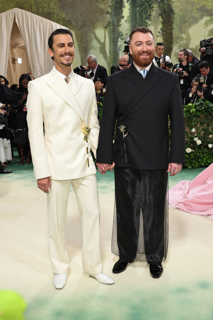 Christian Cowan and Sam Smith hold hands on the red carpet - Photo: Getty