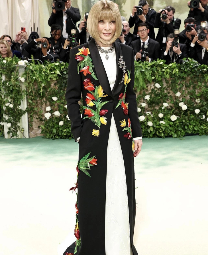 "Chủ xị" Anna Wintour - tổng biên tập Vogue toàn cầu, chủ tịch của Met Gala - chọn đầm tối giản, nhấn bằng áo khoác hoa 3D của Loewe xuất hiện đầy quyền lực