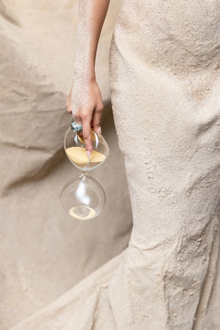 Chiếc túi hình đồng hồ cát bằng thủy tinh do Balmain thiết kế, với cát bên trong, làm nổi bật mối liên hệ với chủ đề thời gian của sự kiện.