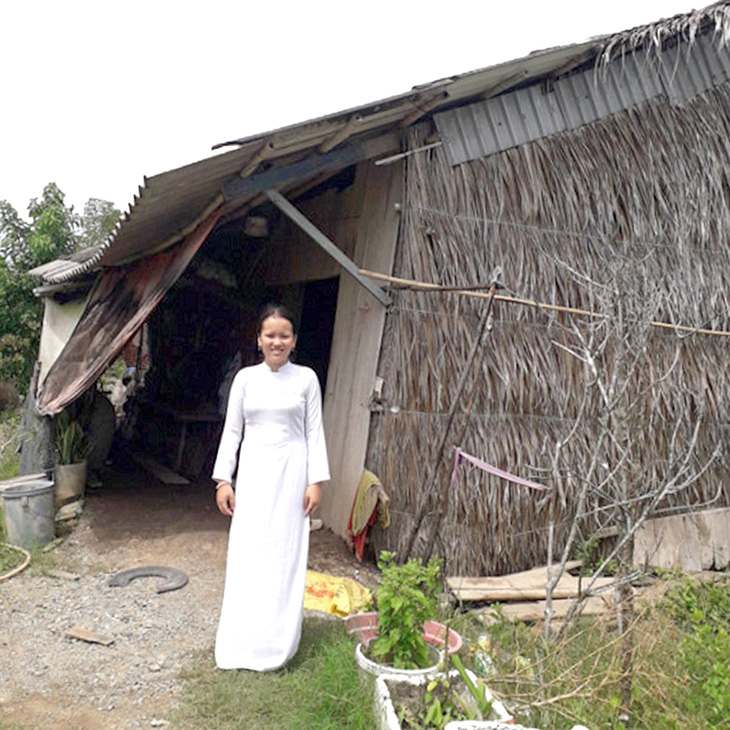 Nguyễn Thị Trà My trước ngôi nhà lá xiêu vẹo là nơi che mưa nắng của 4 người trong gia đình - Ảnh: N.V.HAI