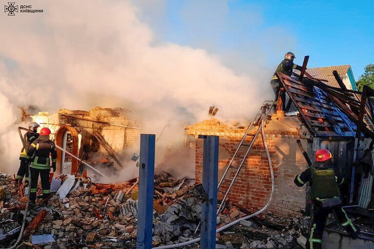 Lính cứu hỏa nỗ lực dập tắt đám cháy tại một công trình bị hư hại sau cuộc tấn công tên lửa của Nga ở vùng Kiev, Ukraine ngày 8-5 - Ảnh: Cơ quan Tình trạng khẩn cấp Ukraine