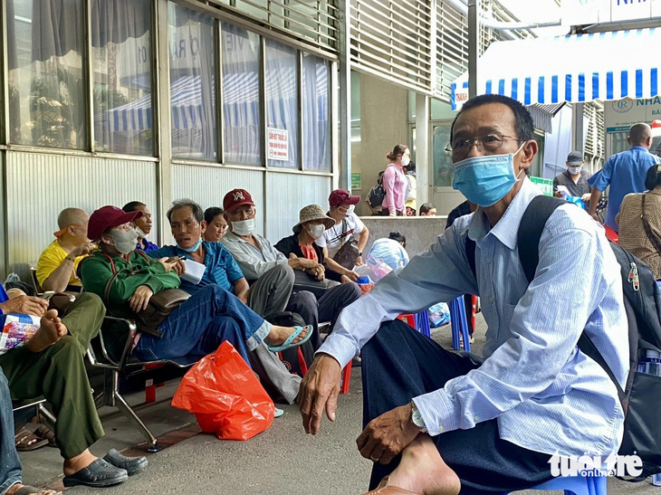 Người bệnh mạn tính ngồi bên ngoài chờ đợi đến lượt mình lãnh thuốc bảo hiểm y tế tại Bệnh viện Chợ Rẫy (quận 5) - Ảnh: NGỌC NHI