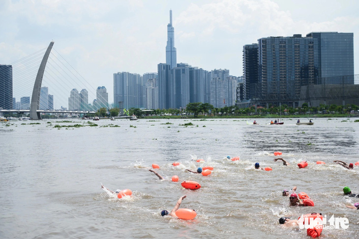 Vận động viên giải bơi vượt sông với những chiếc phao hỗ trợ - Ảnh: PHƯƠNG QUYÊN