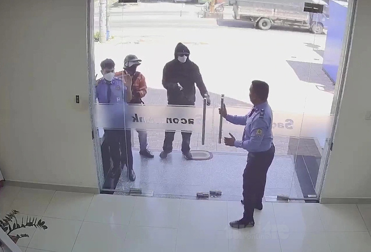 Lợi và Mỹ cầm súng vào khống chế bảo vệ, uy hiếp nhân viên cướp tiền - Ảnh: Cắt từ video
