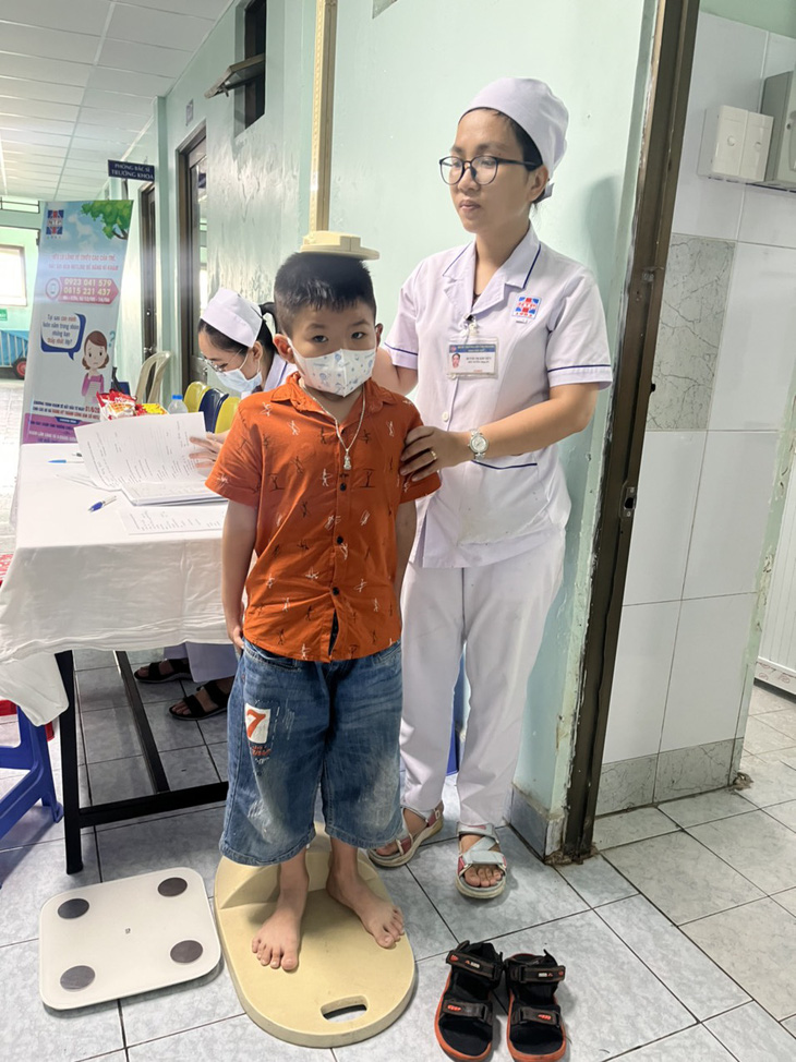 Một bà mẹ ở TP.HCM lo lắng con trai chậm phát triển chiều cao đã đưa con đến Bệnh viện Nguyễn Tri Phương để khám trong ngày 1-6 - Ảnh: THÙY DƯƠNG