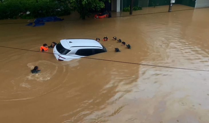 Lực lượng chức năng đang di chuyển một ô tô ra khỏi khu vực ngập sâu ở khu vực chợ Phương Thiện - Ảnh: Nguyễn Cường