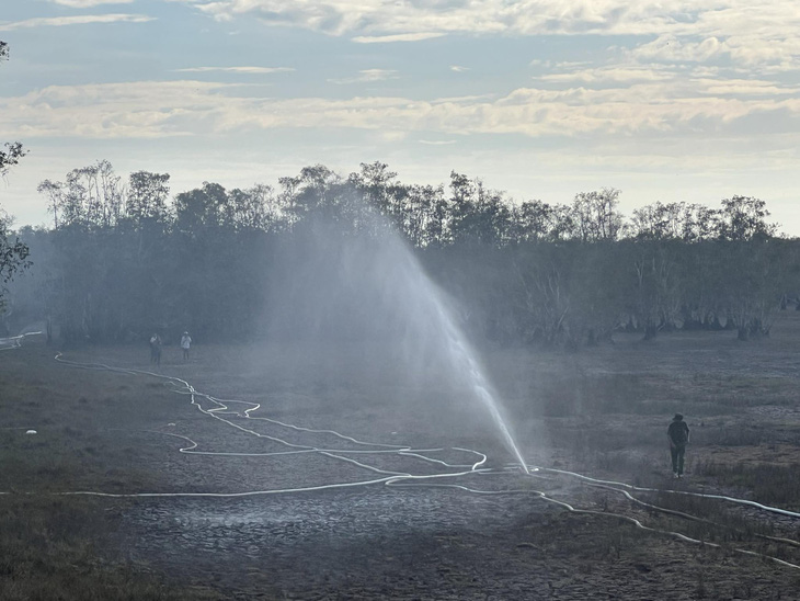 Lực lượng chức năng bơm thêm nước nhằm dập tắt hoàn toàn đám cháy tại Vườn quốc gia Tràm Chim - Ảnh: TỐNG DOANH