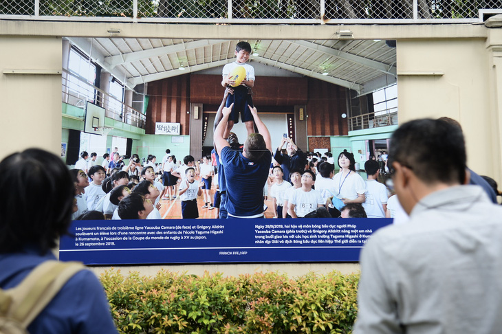 Hai hậu vệ môn bóng bầu dục người Pháp nâng một em nhỏ trong buổi giao lưu với các học sinh Trường Taguma Higashi ở Kumamoto, nhân dịp Giải vô địch bóng bầu dục liên hiệp thế giới diễn ra ở Nhật Bản. Triển lãm của Tổng lãnh sự quán Pháp muốn tôn vinh những khoảnh khắc sẻ chia và tình hữu nghị mà các vận động viên, đội tuyển của họ cũng như công chúng đã trải qua như trong bức ảnh này - Ảnh: HẢI QUỲNH