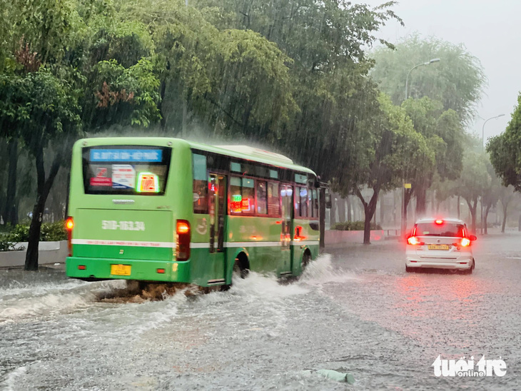 Xe buýt chạy qua tạo thành sóng nước trên đường Lê Lai, quận 1 - Ảnh: LÊ THÀNH HUY