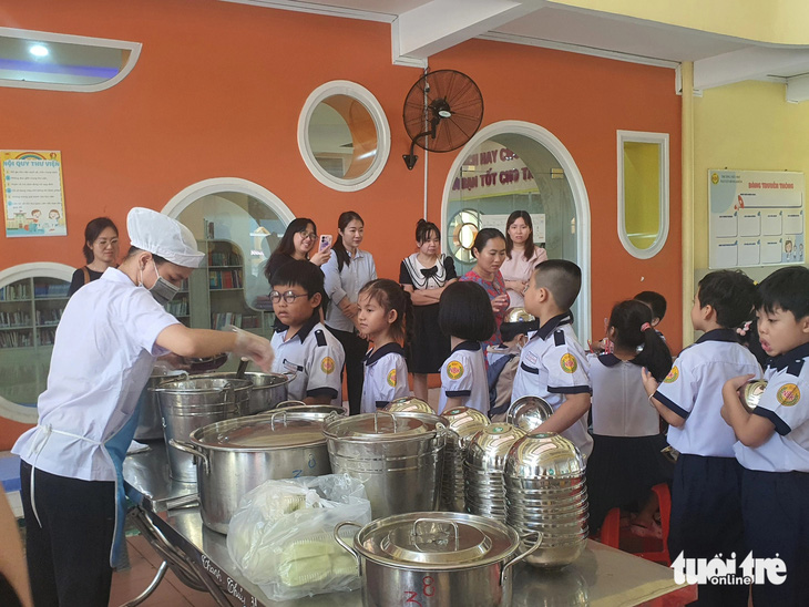 Học sinh Trường tiểu học Nguyễn Bỉnh Khiêm, quận 1, TP.HCM xếp hàng lấy thức ăn trong bữa trưa bán trú - Ảnh: BẢO TRÂN