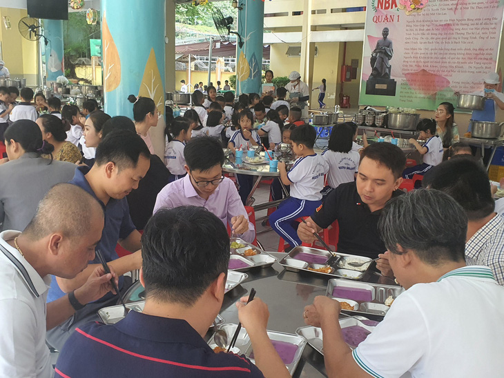 Phụ huynh dùng bữa ăn bán trú tại trường của con để giám sát bữa ăn bán trú tại Trường tiểu học Nguyễn Bỉnh Khiêm, quận 1, TP.HCM - Ảnh: BẢO TRÂN