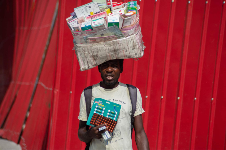 Một người bán hàng rong đội thuốc trên đầu để bán trên đường phố ở Port Au Prince (Haiti) ngày 13-6. Đây là hình ảnh đặc trưng ở Haiti, phản ánh tình trạng y tế khó khăn của nước này trong bối cảnh chính phủ phải ưu tiên an ninh và chống tham nhũng - Ảnh: AFP